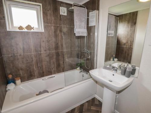 a bathroom with a bath tub and a sink and a bath tubermott at 44 Delamere Point in Northwich