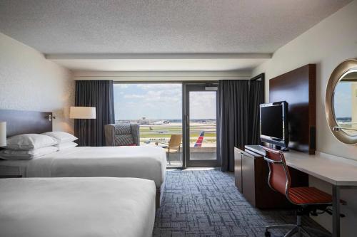 a hotel room with two beds and a desk and a television at Renaissance Concourse Atlanta Airport Hotel in Atlanta