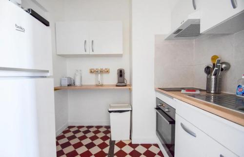a kitchen with white cabinets and a checkered floor at Superbe studio 2 pers tout équipé WIFI & Proche Paris - R2 in Montreuil
