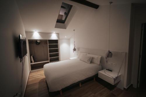 a small bedroom with a white bed and a chair at Apartamentos Lucio Rodinso in Castroverde