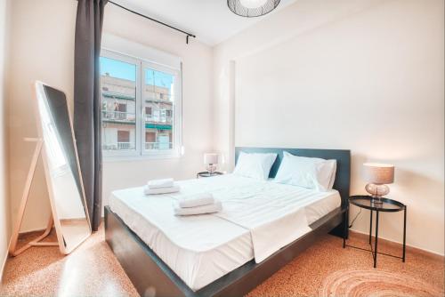 a bedroom with a bed with white sheets and a window at Koukaki Apartment in Athens