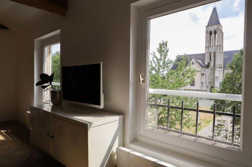 Cette chambre dispose d'une fenêtre, d'une télévision et d'une église. dans l'établissement Duplex Downtown Abbaye by La Boîte En Plus, à Senlis