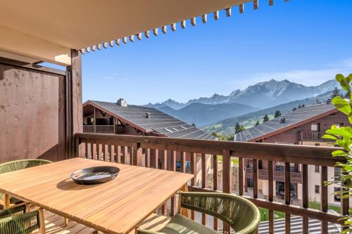 a wooden table on a balcony with a view of mountains at Stunning flat with views of Mont Blanc in Combloux - Welkeys in Combloux