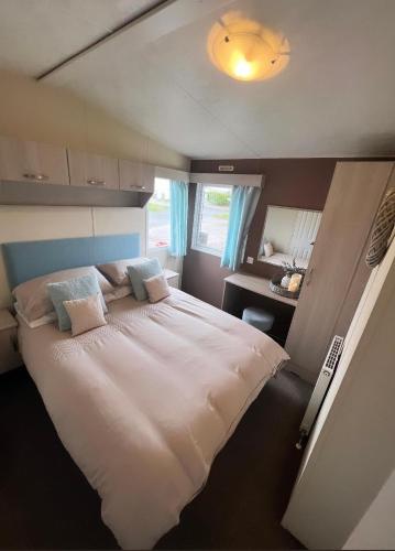 una camera da letto con un grande letto bianco e una scrivania di At The Waters Edge ( Wansbeck View 26 ) a Newbiggin-by-the-Sea