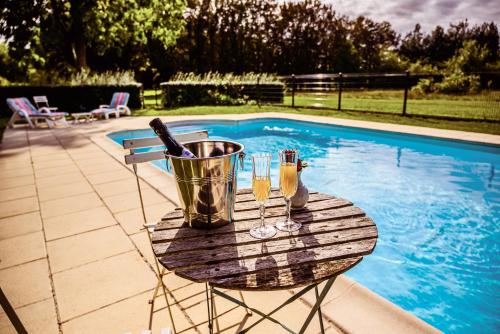 - une table avec deux boissons et un seau à côté de la piscine dans l'établissement Château de la Grange Moreau, à Vallon-sur-Gée