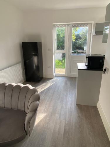 an empty living room with a couch and a television at Gladys’ Apartment in Ponders End