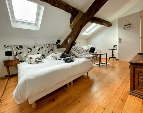 une chambre avec un grand lit blanc et du parquet dans l'établissement Les Mirabelles, à Tournon-dʼAgenais
