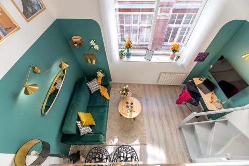 un salon avec un canapé vert et une fenêtre dans l'établissement Calliopée by Kleidos - Magnifique duplex, Gros Horloge Rouen, à Rouen