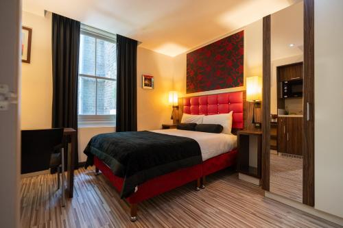 a bedroom with a large bed with a red headboard at Simply Rooms & Suites in London