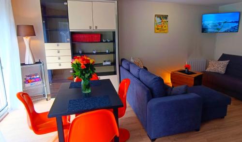 uma sala de estar com um sofá azul e uma mesa com cadeiras vermelhas em Appart pour 5 - Centre-ville em Caen