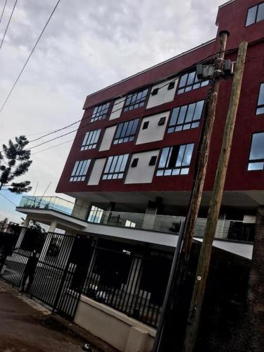 a large red building with windows on a street at Spacious studio apartment in a modern high-security building with lift access Includes free parking in Muyenga kampala in Kampala