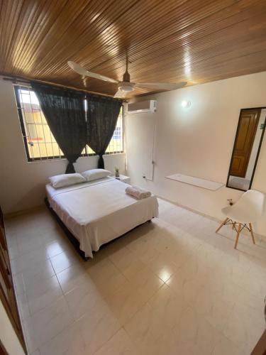 een grote slaapkamer met een bed en een stoel bij Habitaciones cerca al aeropuerto 2 in Cartagena
