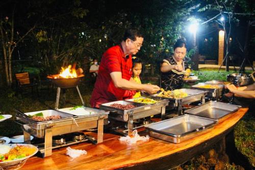 un grupo de personas de pie alrededor de una mesa con comida en Bat Rice Resort, en Battambang
