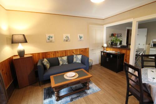 een woonkamer met een blauwe bank en een tafel bij Appartement dans Maison in Plainfaing