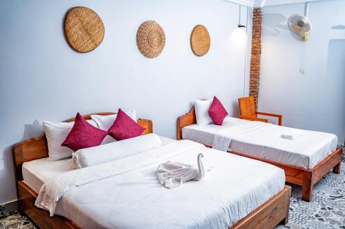 Bat Rice Resort في باتامبانغ: سريرين في غرفة مع وسائد وردية