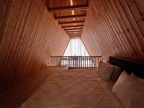 a bed in a wooden room with a window at Topchu Forest Ismayilli in Topçu