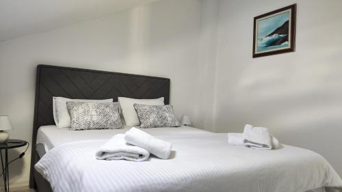 a bedroom with a white bed with towels on it at Apartman Polaris Posušje in Posušje