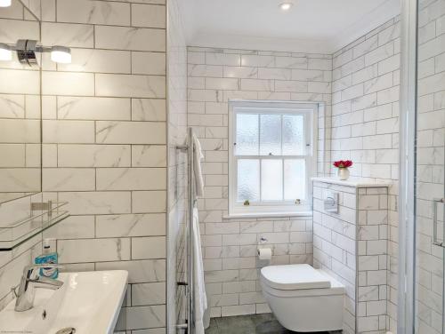 a white bathroom with a toilet and a sink at 5 The Clock House in Midhurst