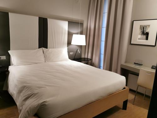 a bedroom with a large white bed and a desk at Hotel Casa Poli in Mantova