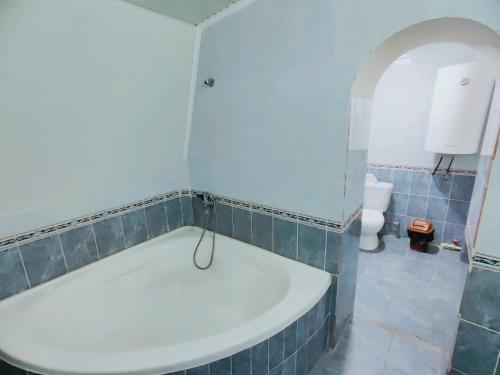 a bath tub in a bathroom with a toilet at Hotel Zavq in Andijan