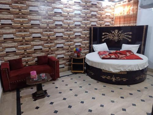a bedroom with a large bed and a chair at Faizan Hotel in Lahore