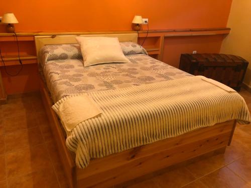 1 cama en un dormitorio con 2 lámparas en la pared en Casa Rural La Curva, en Barajas de Gredos