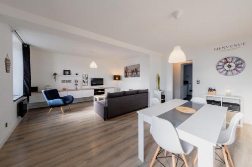 una sala de estar blanca con mesa blanca y sillas en Gîte de la Place classé 3 étoiles Centre Bourg WIFI Services prosConciergerie Comte des Cierges, 