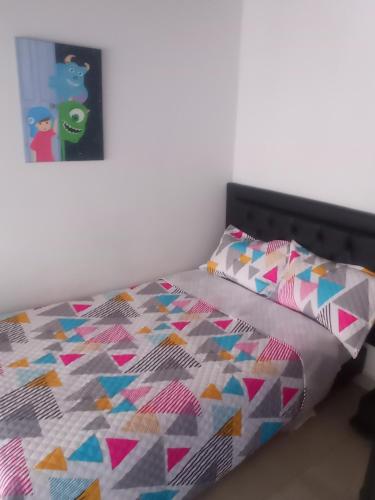 a bed with a colorful quilt and a picture on the wall at Casa b in Itagüí