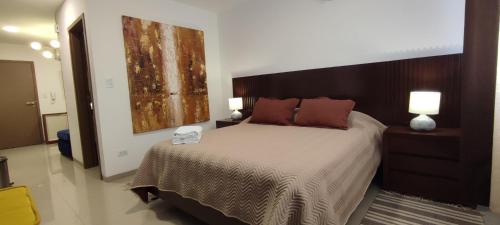 - une chambre avec un grand lit et une tête de lit en bois dans l'établissement APARTAMENTO MODERNO EN EQUIPETROL, CON CINE - PISCINA - GYM y PARQUEO GRATUITO. Proximo a Los Tajibos, Ventura Mall, SUPER ICENORTE, à Santa Cruz de la Sierra