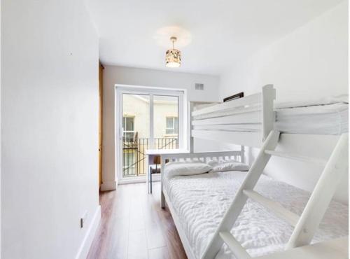 a white bedroom with a bunk bed and a desk at Coastal Apartment Tramore in Waterford
