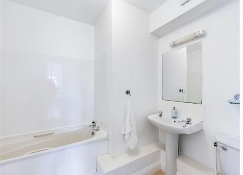 a white bathroom with a bath tub and a sink at Coastal Apartment Tramore in Waterford