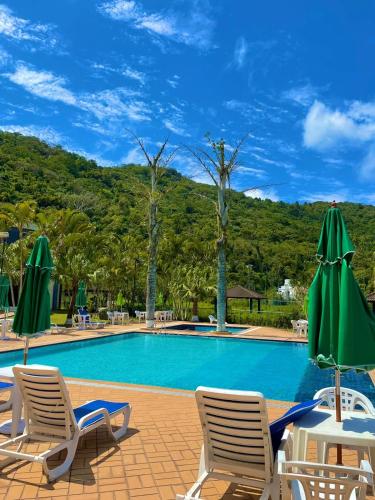 a swimming pool with chairs and umbrellas in a resort at HANNA Canto da Ilha Hotel & Eventos in Florianópolis