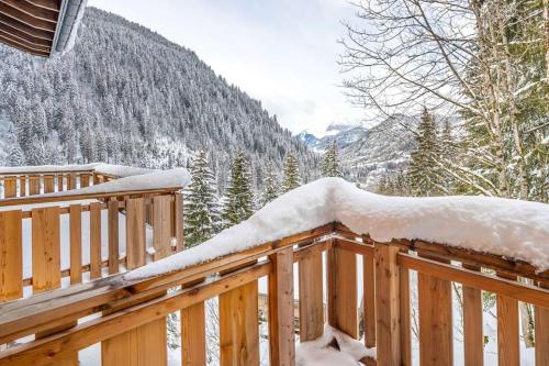 une terrasse en bois recouverte de neige avec des montagnes en arrière-plan dans l'établissement Les Freinets - Apt D303 - BO Immobilier, à Châtel
