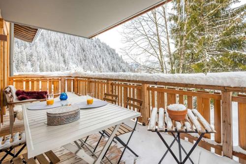 une table et des chaises blanches sur une terrasse enneigée dans l'établissement Les Freinets - Apt D303 - BO Immobilier, à Châtel