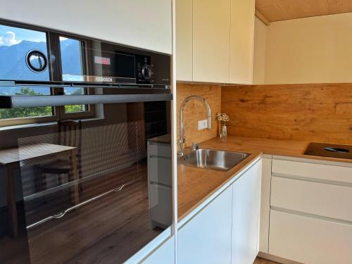 a kitchen with white cabinets and a sink and a window at Alpenstern Apartment Montafon in Sankt Gallenkirch