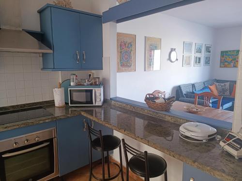 una cocina con armarios azules y una barra con taburetes en Casa de Famara, en Famara
