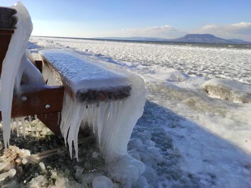 a bench covered in ice in a snowy field at Sunshine Villa Fonyódliget in Fonyód