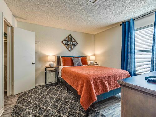 1 dormitorio con cama con sábanas de color naranja y ventana en OU Boomer, Pool & Gym, BBQ, Roku TVs, 100mb Internet, Washer & Dryer, just one mile to OU!, en Norman