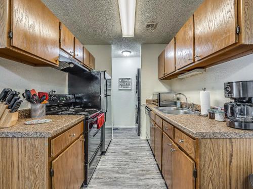 a kitchen with wooden cabinets and a stove top oven at OU Sooner, Pool & Gym, BBQ, Netflix, 100mb Internet, LG Washer & Dryer, Close to OU! in Norman