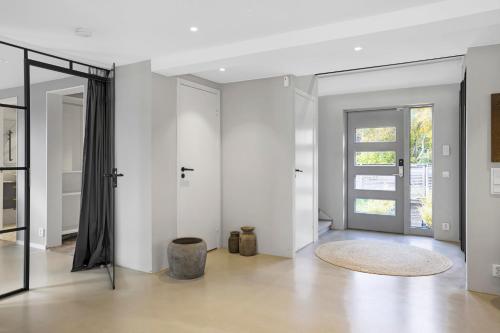 a living room with white walls and a glass door at Hyr villa i Stenhuggeriet nära till både hav och golf in Halmstad