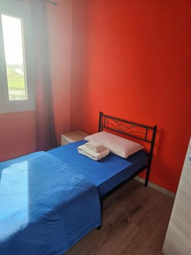 1 dormitorio con 1 cama azul y pared de color naranja en happy house fiume veneto 1, en Bannia