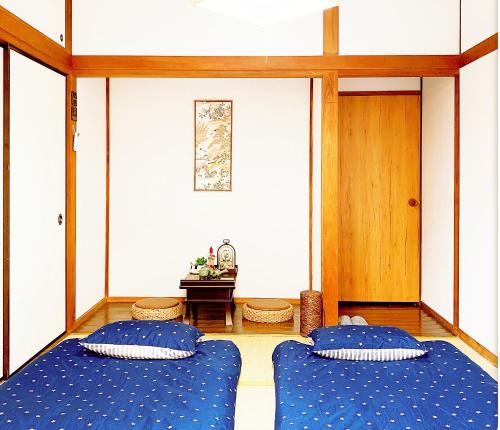 2 camas azules en una habitación con una cruz en la pared en TOKYO/Shinjuku & Shibuya 10mins/5mins walk to subway stiaon/Kichijoji 15mins/Shimokitazawa 5mins/Louis House, en Tokio