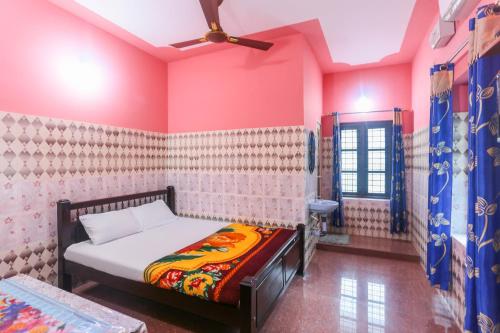 a bedroom with a bed in a room with pink walls at OYO Hotel Sree Bhadra Tourist Home in Kollam