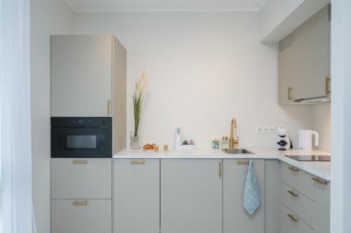 a white kitchen with white cabinets and a black appliance at Fortune Apartments - River view, Contactless in Tartu