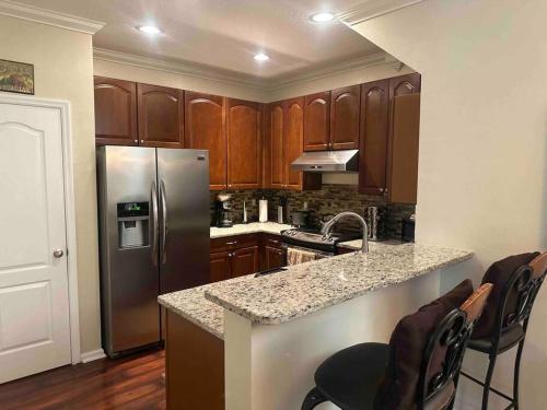 a kitchen with wooden cabinets and a stainless steel refrigerator at Townhome Baptist South St JohnsTownCenter Beach in Jacksonville