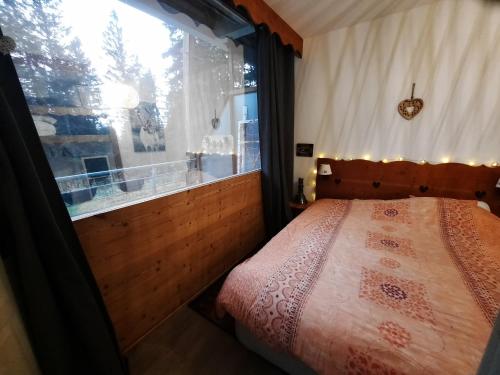 ein Schlafzimmer mit einem Bett und einem großen Fenster in der Unterkunft La Petite Foret Chamrousse 1700 in Chamrousse