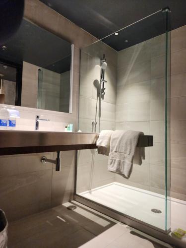 a bathroom with a glass shower and a sink at Grand Hotel Times Levis in Lévis