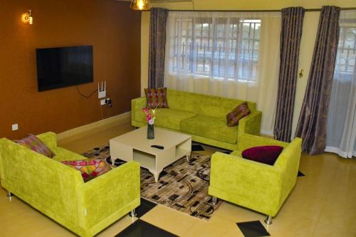 sala de estar con sofás verdes y TV en The Green Baroness, en Eldoret