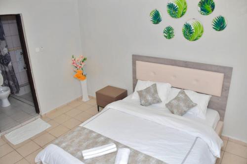 Un dormitorio con una cama blanca y un jarrón de flores en The Green Baroness, en Eldoret