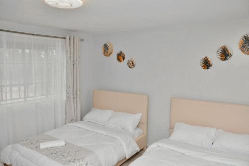 2 camas en un dormitorio con mariposas en la pared en The Green Baroness, en Eldoret